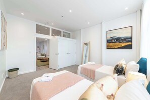 A modern bedroom with two beds, a large window, and a painting on the wall. - The Hudson | 3BR Bright Courtenay Place Townhouse (Wellington)