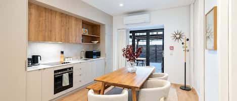 Una cocina moderna con una mesa y sillas de madera, un microondas y una cafetera.