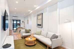 A modern living room with a sofa, armchairs, a coffee table, and a flat-screen TV. - The Hudson | 3BR Bright Courtenay Place Townhouse (Wellington)