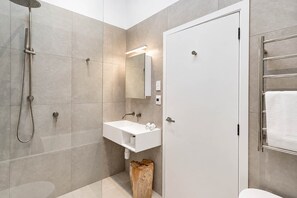 Une salle de bain moderne avec une douche, un lavabo et un miroir.