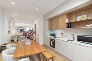 A modern kitchen with white cabinetry, a wooden dining table, and a built-in oven. - The Hudson | 3BR Bright Courtenay Place Townhouse (Wellington)