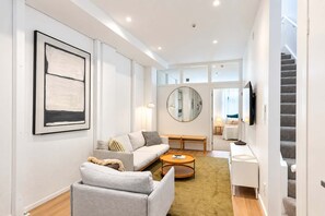 A modern living room with a sofa, a round coffee table, and a television. - The Hudson | 3BR Bright Courtenay Place Townhouse (Wellington)