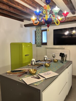 Eine Küche mit einem grünen Kühlschrank, einer Bar mit Gläsern und einer Flasche sowie einem an der Wand befestigten Fernseher.