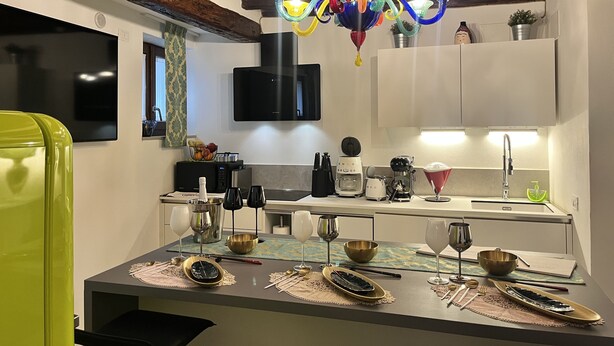 Una cocina moderna con techo de madera, una lámpara de cristal de colores y un comedor listo para una comida.