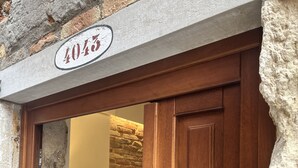 Entrada de un edificio con fachada de piedra, una puerta de madera y una placa con el número 4045.
