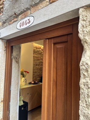 Ein Gebäudeeingang mit einer steinernen Fassade, einer Holztür und einem Nummernschild mit der Aufschrift '4045'.