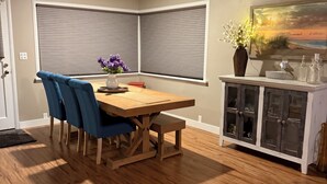 Uma sala de jantar com uma mesa de madeira, cadeiras azuis e um armário com portas de vidro.