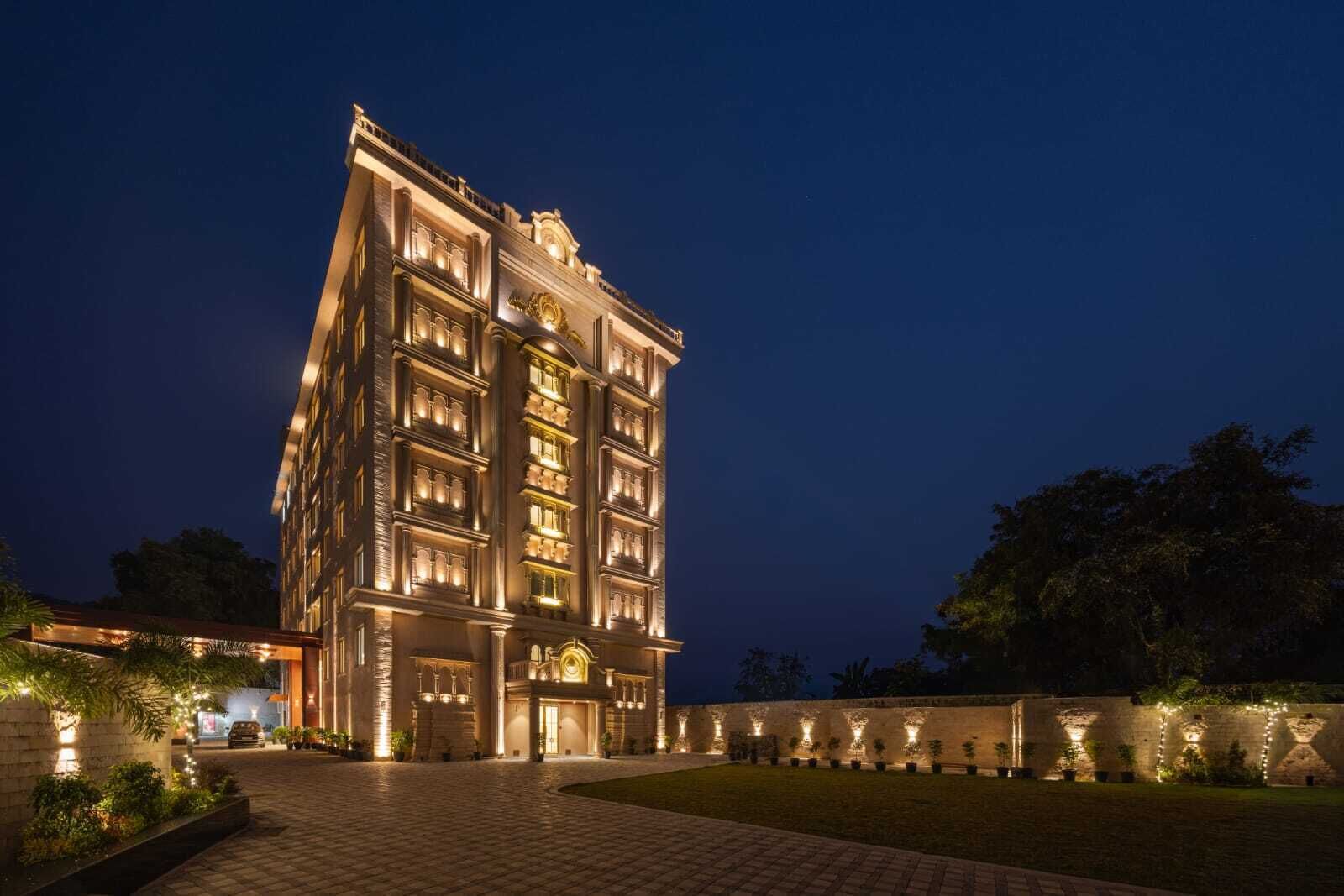 A multi-story hotel with a grand entrance, a well-lit facade, and a paved courtyard.