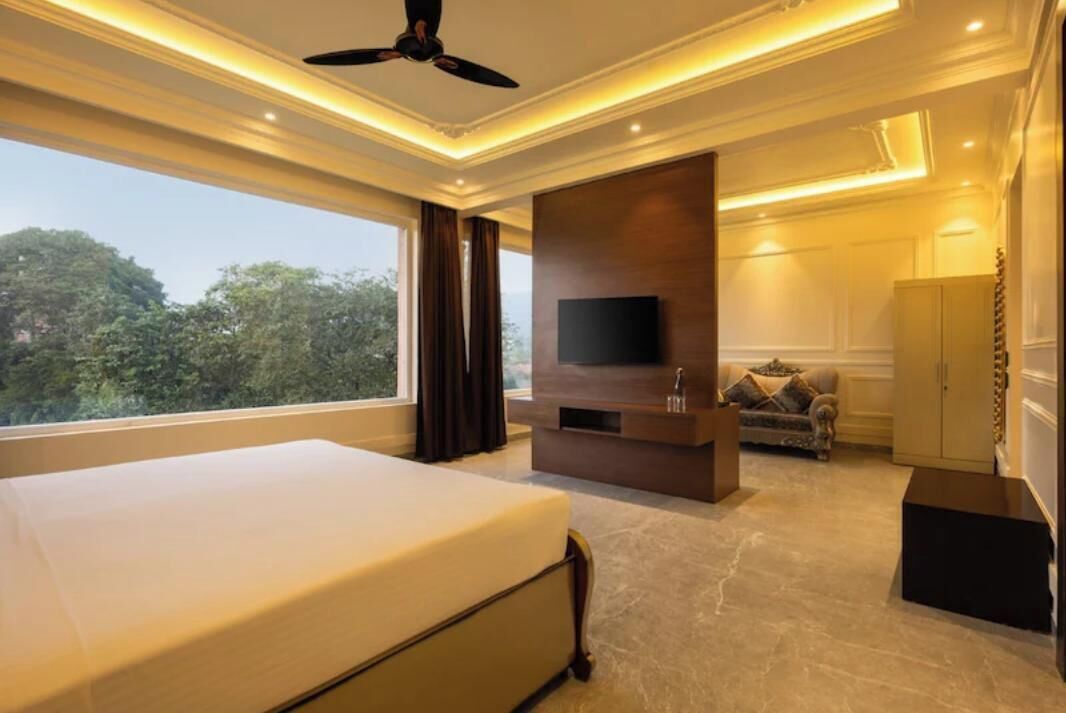 A bedroom with a large bed, a TV, a sofa, and a wardrobe.