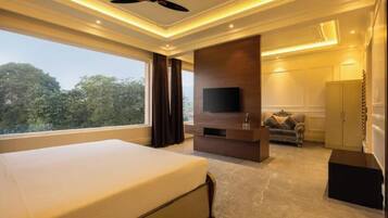 A bedroom with a large bed, a TV, a sofa, and a wardrobe.