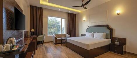 Habitación de hotel con cama, escritorio, silla y televisor.