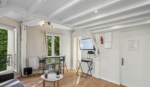 Ein modernes Zimmer mit Esstisch, Stühlen, einem Fernseher und einem Feuerlöscher.