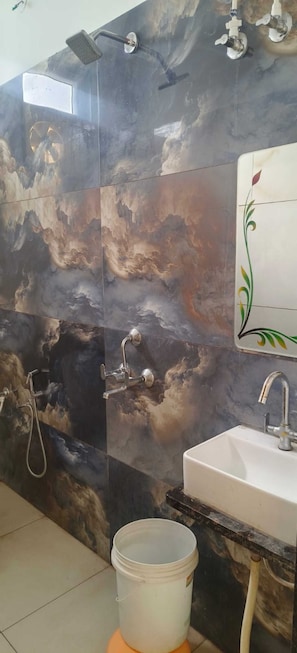 Een badkamer met een douche, wastafel en decoratieve wand.