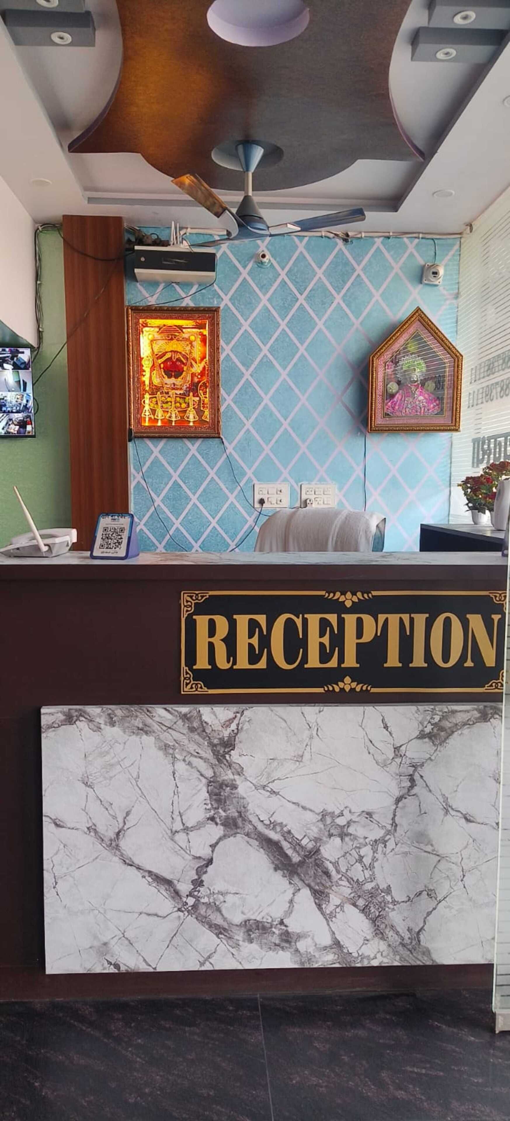 A reception desk with a marble top, framed artwork on the wall, and a ceiling fan.
