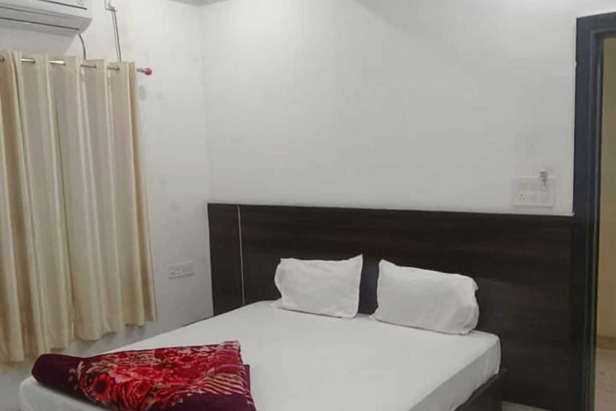 Un dormitorio con cama, ventilador de techo, ventana con cortinas y puerta.