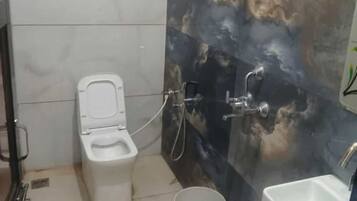 Un baño con inodoro, ducha, lavamanos y un ventilador en la pared.