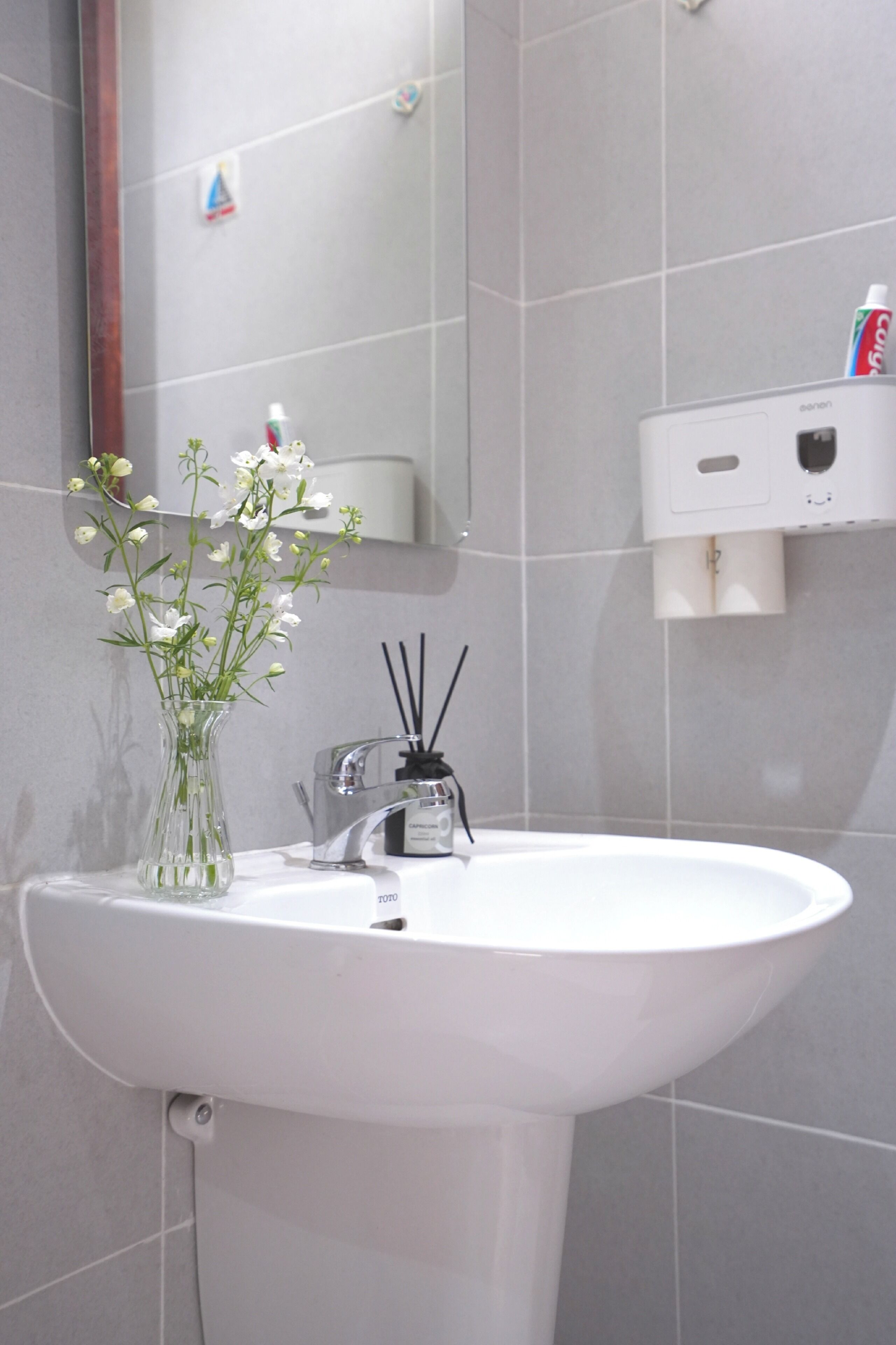 A bathroom with a white sink, a mirror, and a dispenser.