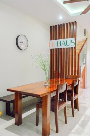 A wooden dining table with chairs, a clock, and a sign on the wall.