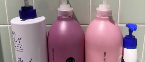 Une étagère de salle de bain avec trois flacons de produits capillaires et un récipient blanc.