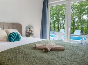A hotel room with a bed, a view of a swimming pool, and a large window. - Villa Peace Oasis (Lovreć)