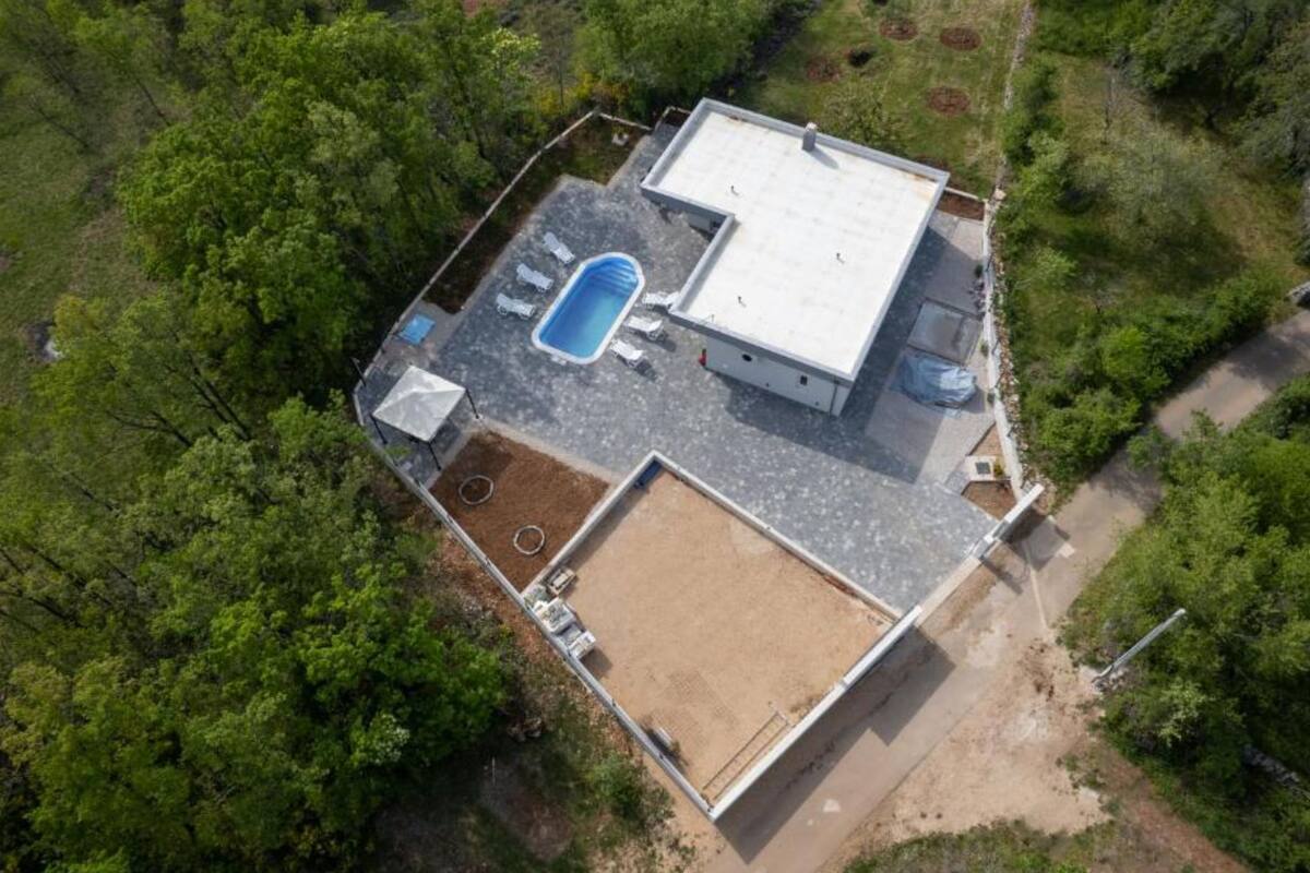 Vista aérea de una casa con piscina, un porche cubierto y un patio cercado.