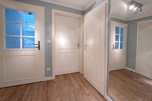 Een kamer met een houten vloer, witte deuren en een raam.