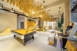 A pool table, seating area, and arcade machines in a well-lit indoor space. - Jianshanxi Designer Hotel (Ngawa Autonomous Prefecture)