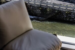 A stone bridge over a flowing river, a railing, and a view of the water.