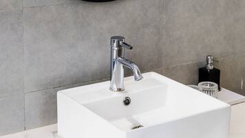 Un baño con un espejo redondo, un lavabo blanco y una puerta de madera.