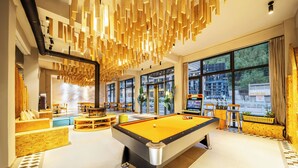 A pool table in a well-lit room with large windows, wooden decor, and seating areas. - Jianshanxi Designer Hotel (Ngawa Autonomous Prefecture)
