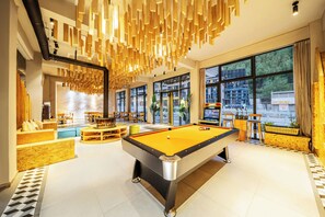 A pool table in a modern room with large windows, a seating area, and a view of the city. - Jianshanxi Designer Hotel (Ngawa Autonomous Prefecture)
