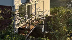 Un bâtiment à deux étages, doté d’un toit recouvert de tuiles rouges, d’un petit balcon et d’un appareil de climatisation installé au rez-de-chaussée.