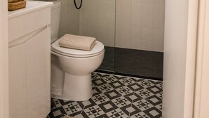 Une salle de bain avec des toilettes, une douche et un carrelage décoratif.