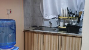 Kompakti keittiö, jossa on puiset kaapit, pesuallas, vesihana ja lattialla erilaisia mausteita.