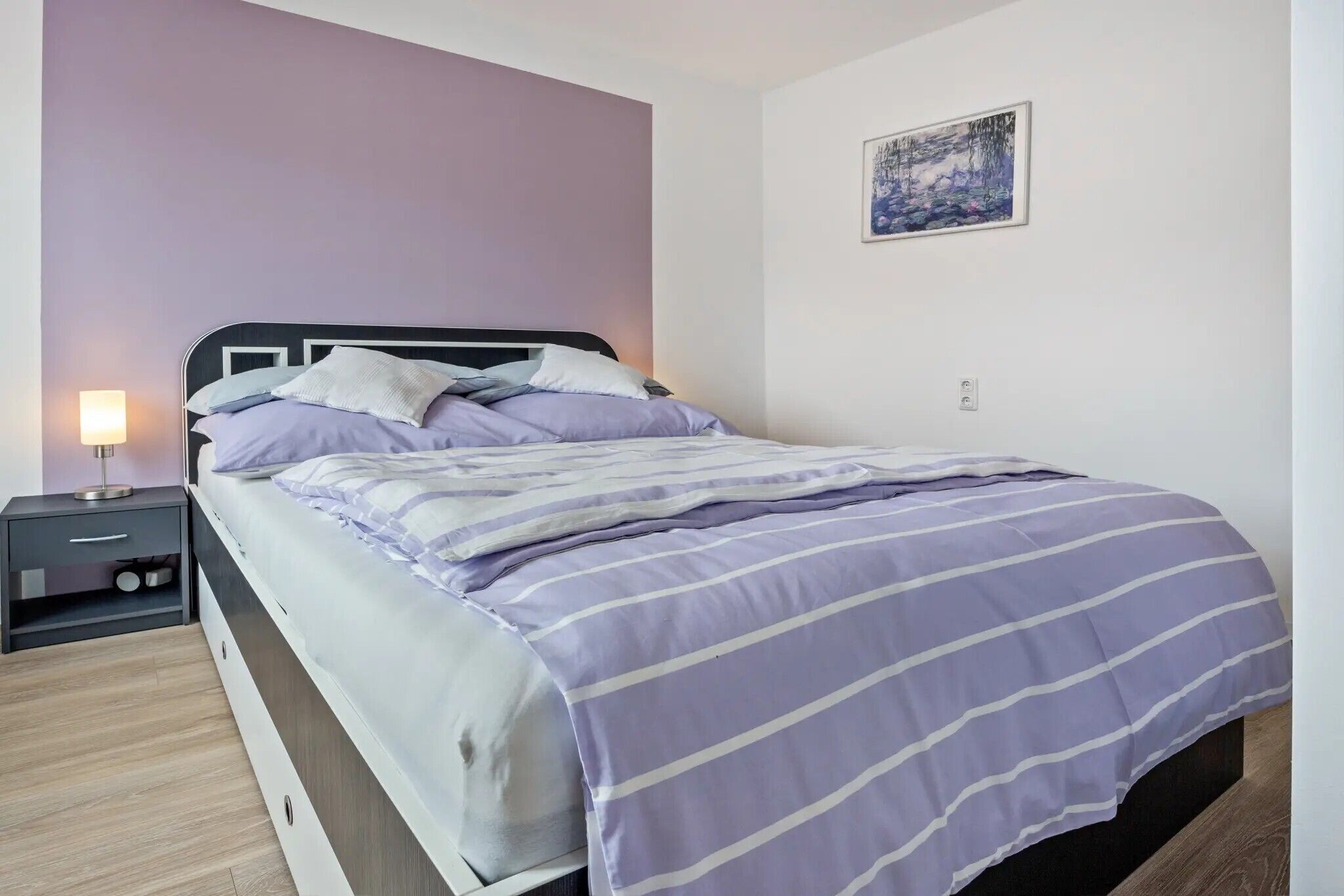 Ein Schlafzimmer mit Bett, Nachttisch und Wandbildern.