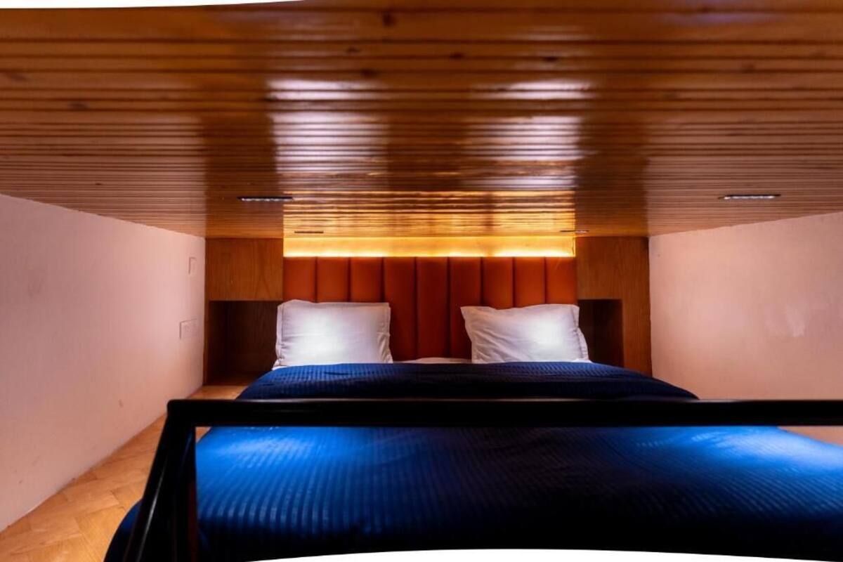 A bedroom with a wooden ceiling, a bed with a blue bedspread, and a red headboard.