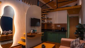 Een modern interieur met een bank, een houten tafel, een aan de muur bevestigde televisie, en een keuken met houten kasten en een aanrecht.
