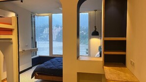 Een moderne slaapkamer met een bed, inbouwkasten, een raam met uitzicht en een houten bureau.