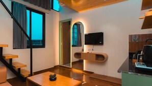 Een modern interieur met een trap, een aan de muur bevestigde flatscreen televisie, een houten tafel en een keuken met een aanrecht.