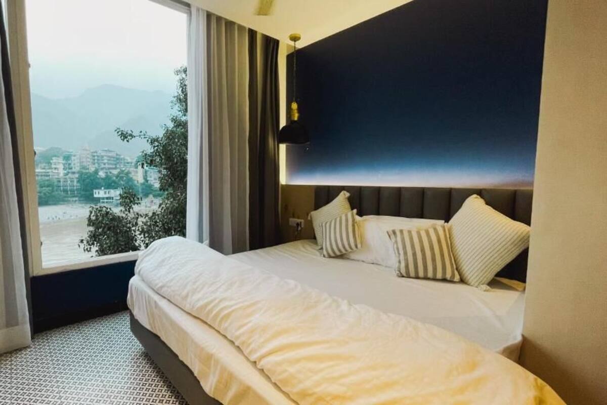 A hotel room with a large bed, a view of the outdoors, and a modern headboard.
