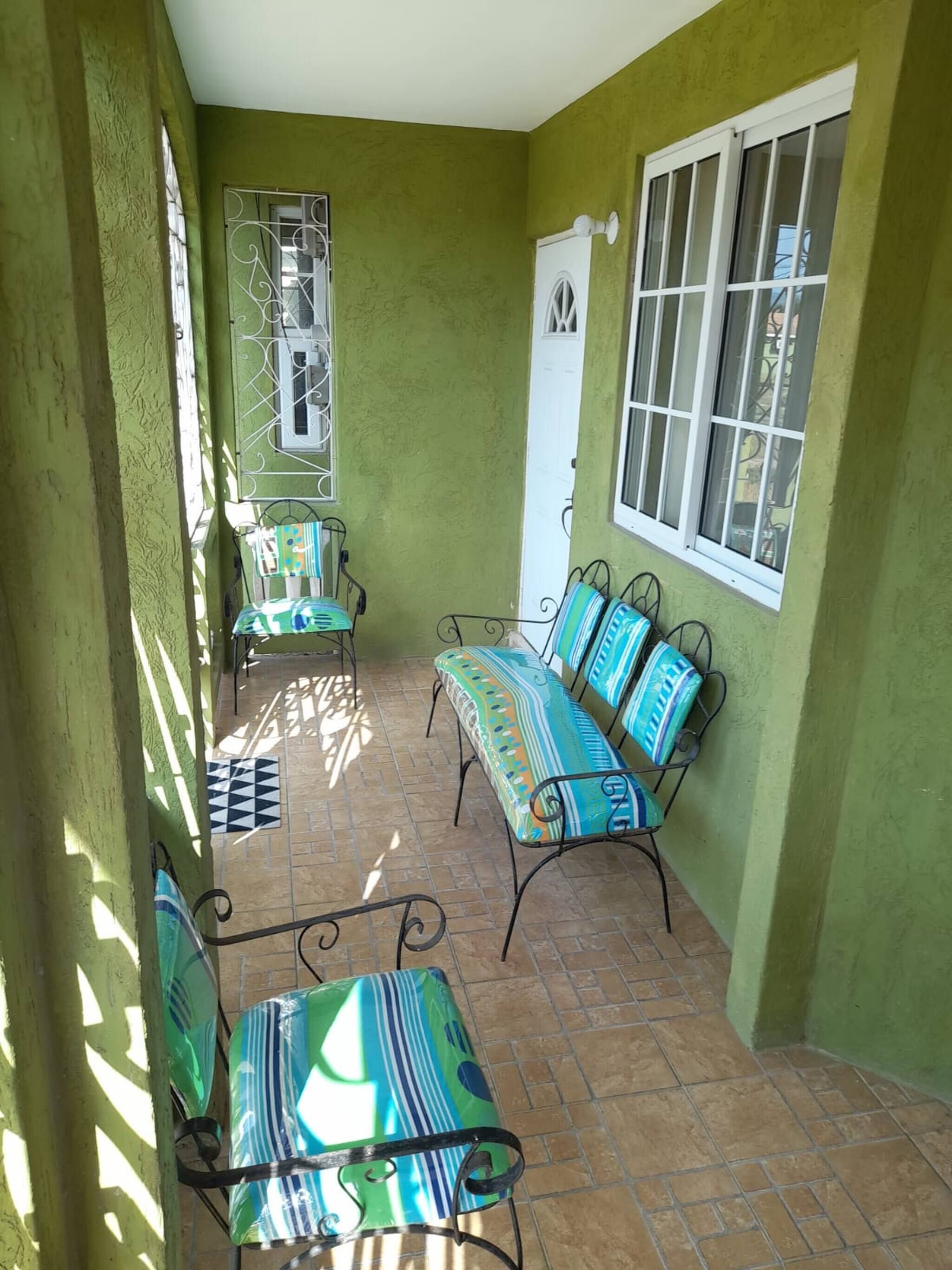 Un portico coperto con un muro verde, una porta e una finestra.