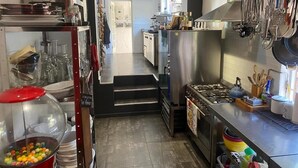 Una cucina moderna con elettrodomestici in acciaio inossidabile, diversi utensili e una vista libera sulla zona pranzo.