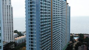 Un grand hôtel à plusieurs étages, doté d’une piscine et offrant une vue sur la mer.