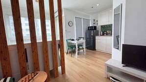 Un appartement moderne comprenant un coin repas, une cuisine et un téléviseur posé sur un meuble.