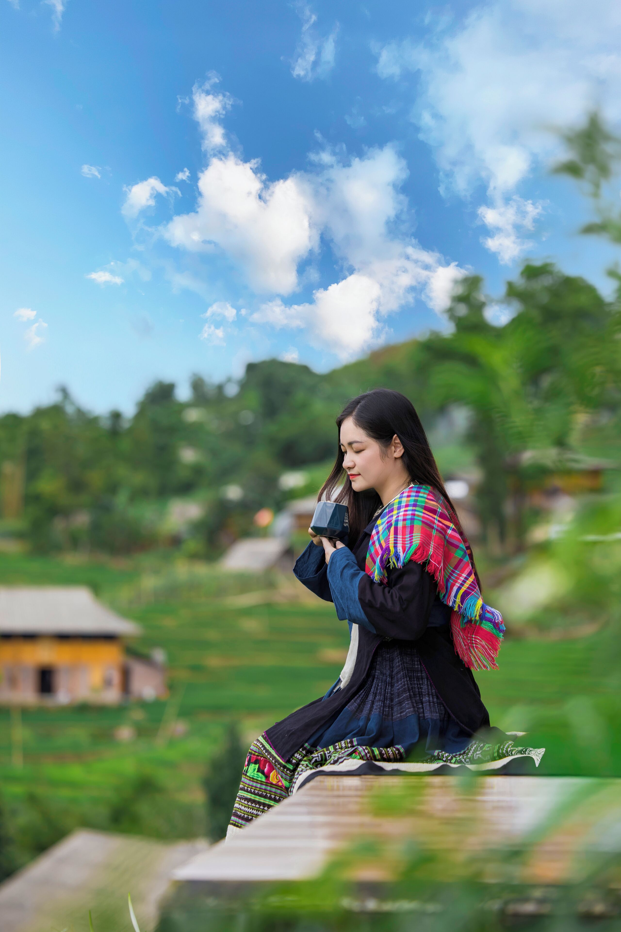 A person sitting on a ledge with a rural landscape in the background.