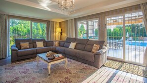 A living room with a sectional sofa, a coffee table, and a chandelier. - Premium 4 bedroom villa in Oludeniz (Fethiye)