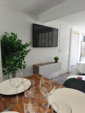 Un coin repas avec une table en bois, de la vaisselle transparente et une plante en pot.