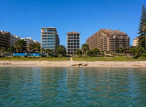 Ein Strandhotel mit mehreren Hochhäusern, klarem, blauem Wasser und Palmen.