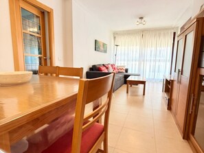 Ein Essbereich mit Holztisch und -stühlen, einer Couch und einem Fenster mit Vorhängen.