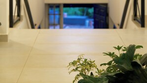 Um interior moderno com uma escada, um lustre e uma vista pela janela.